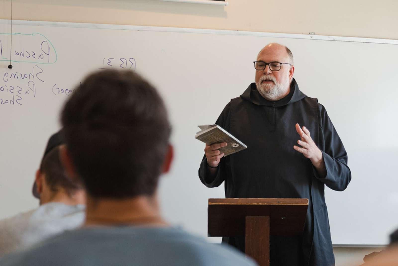 Monk teaching theology at a whiteboard